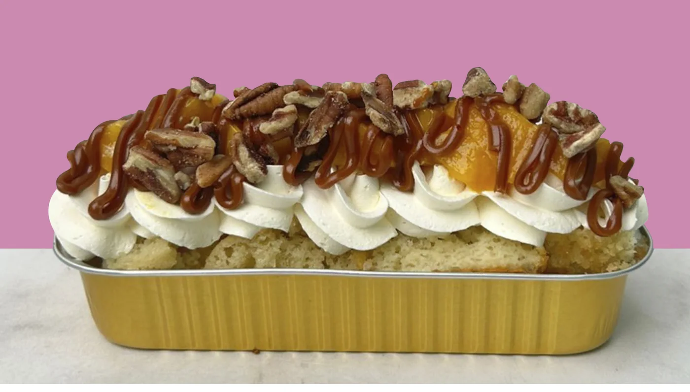 Pastel individual tres leches del Cake Bar en charolita dorada, con crema, durazno, cajeta y nuez