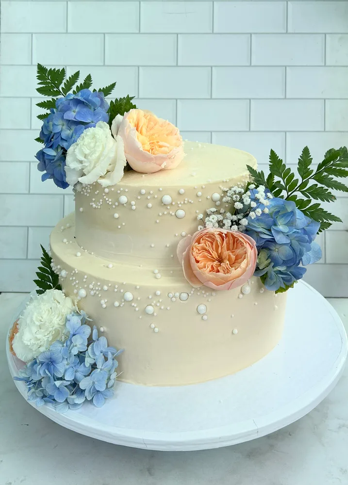 Pastel blanco hortensias azules y rosas durazno